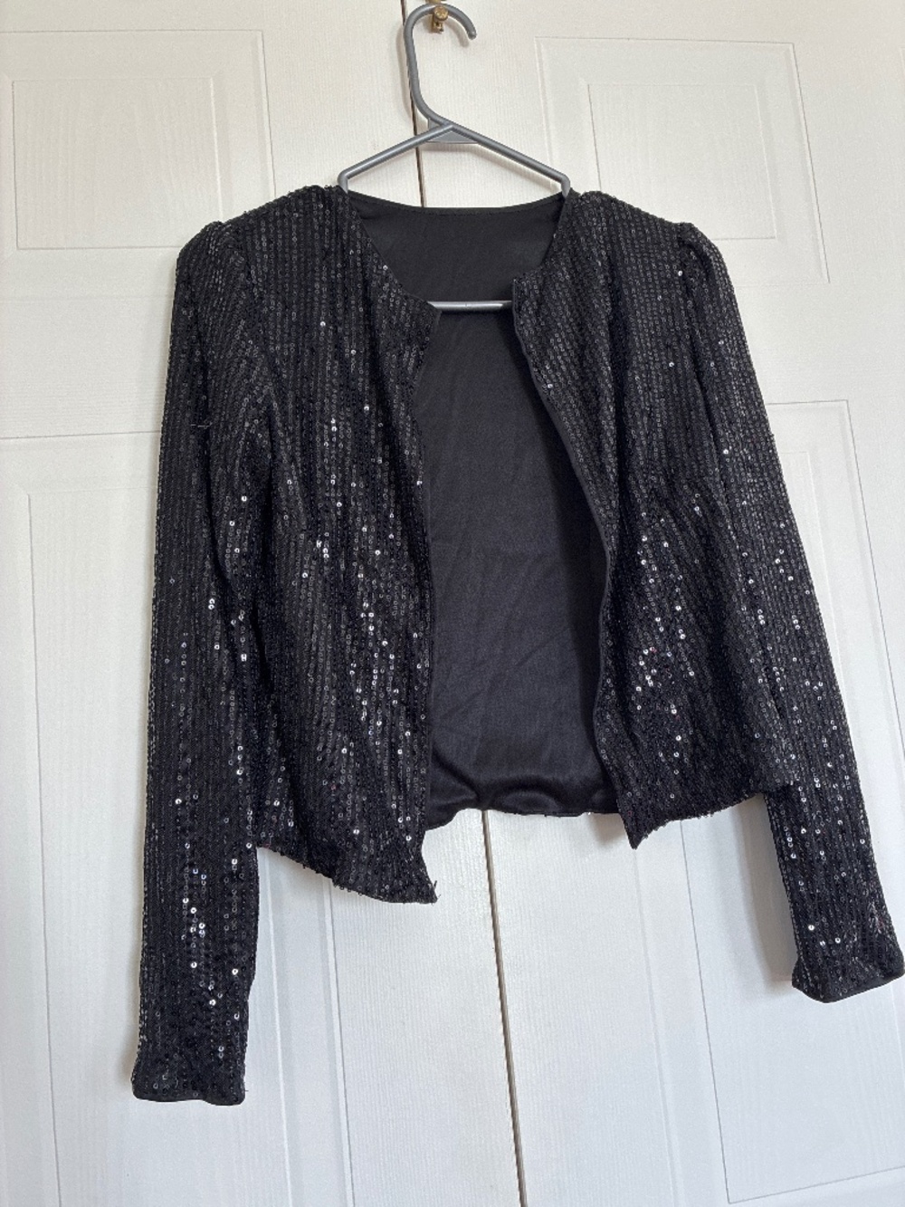 A subtle and perfect black long-sleeve, sequin-embellished cropped top or jacket